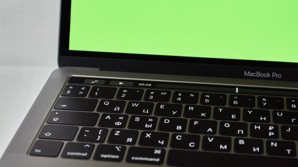 Russian keyboard MacBook Pro with a green screen. Modern electronic device.